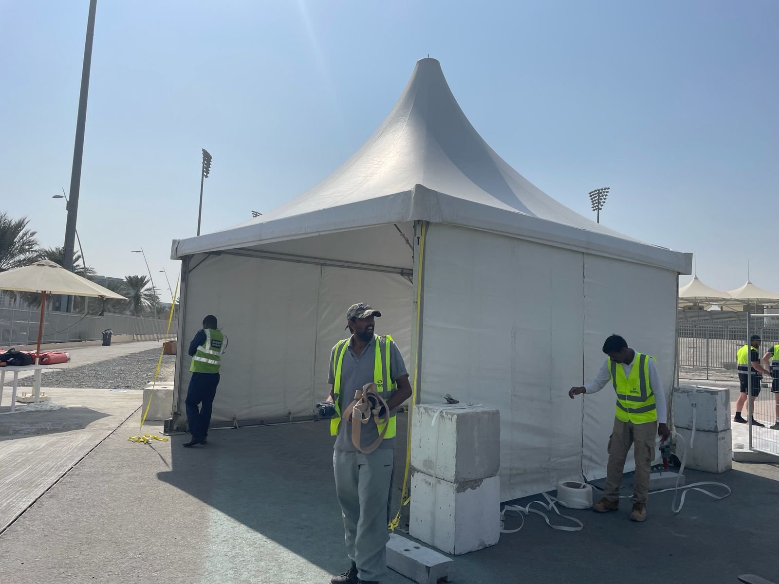 Toko crew installing a single white pagoda tent at a stadium