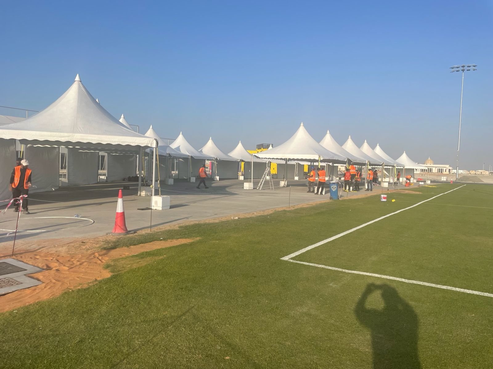 Row of white pagoda tents installed along a sports field for an event